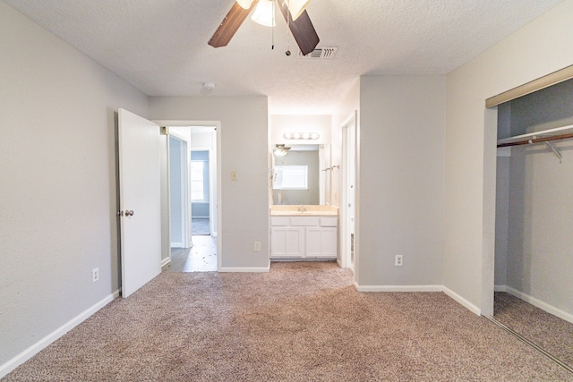 unfurnished bedroom with a closet, ceiling fan, light carpet, and connected bathroom