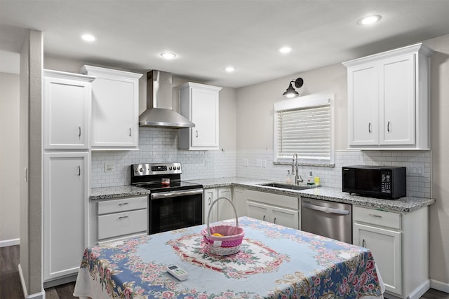 kitchen with wall chimney exhaust hood, dark hardwood / wood-style floors, appliances with stainless steel finishes, sink, and tasteful backsplash