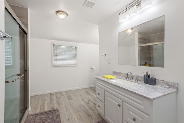 bathroom featuring wood-type flooring, vanity, and a shower with shower door