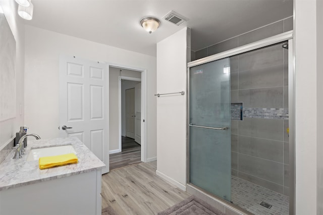 bathroom featuring vanity, hardwood / wood-style flooring, and a shower with shower door