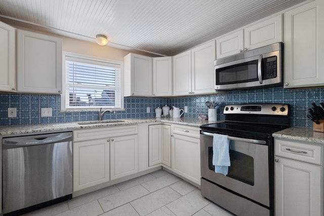 kitchen featuring backsplash, stainless steel appliances, light stone counters, white cabinets, and sink