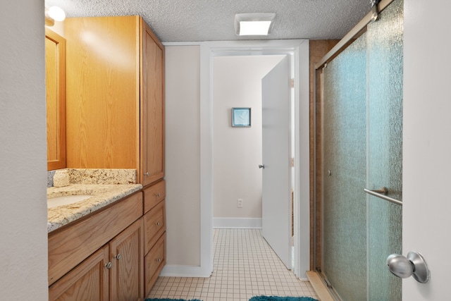 bathroom with vanity with extensive cabinet space, an enclosed shower, tile floors, and a textured ceiling