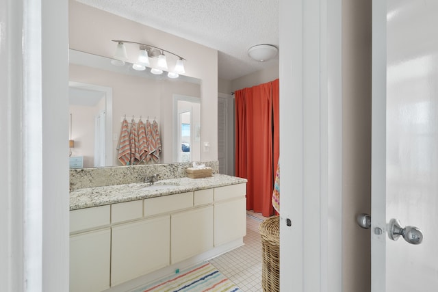 bathroom featuring tile flooring, vanity, and a textured ceiling