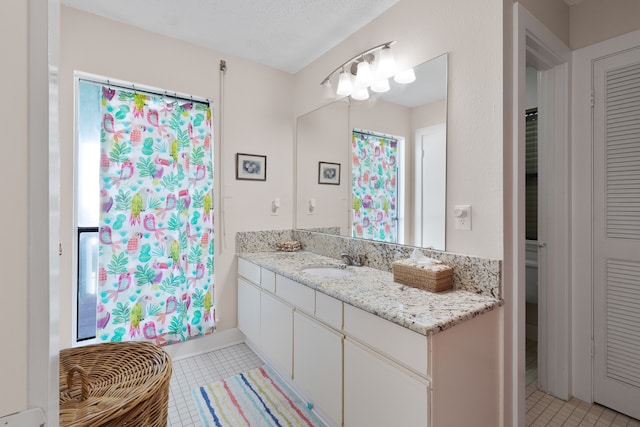 bathroom with a textured ceiling, vanity, and tile flooring