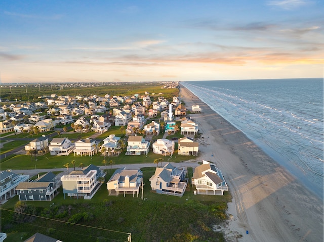 aerial view at dusk with a water view and a beach view