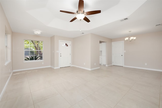 tiled empty room with ceiling fan with notable chandelier and a raised ceiling