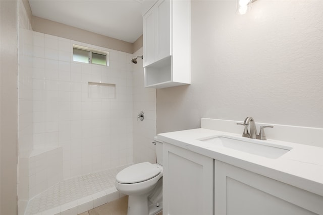 bathroom featuring vanity, a tile shower, and toilet