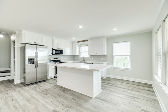 kitchen featuring crown molding, white cabinetry, appliances with stainless steel finishes, tasteful backsplash, and light hardwood / wood-style floors