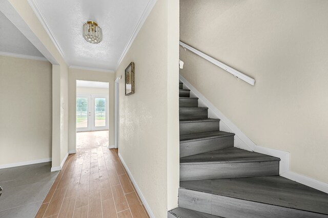 stairway with hardwood / wood-style flooring and crown molding