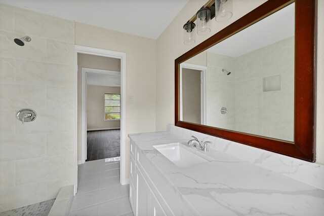 bathroom featuring tiled shower, vanity with extensive cabinet space, and tile flooring