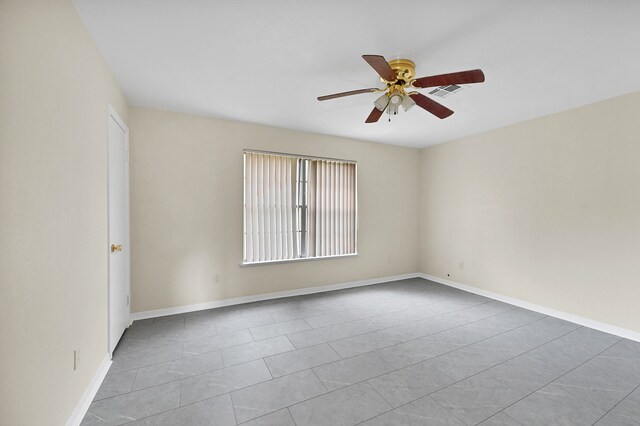 tiled spare room featuring ceiling fan