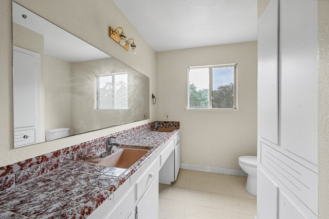 bathroom featuring toilet, tile flooring, and dual vanity