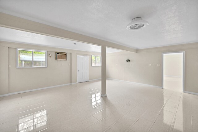 tiled spare room with a textured ceiling and an AC wall unit