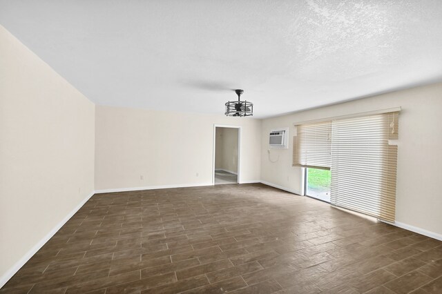 empty room with a wall mounted AC, a chandelier, and a textured ceiling