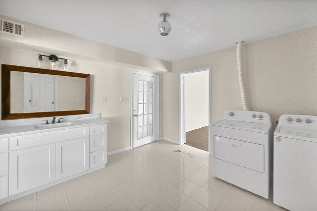 washroom featuring cabinets, sink, washing machine and dryer, and light tile floors