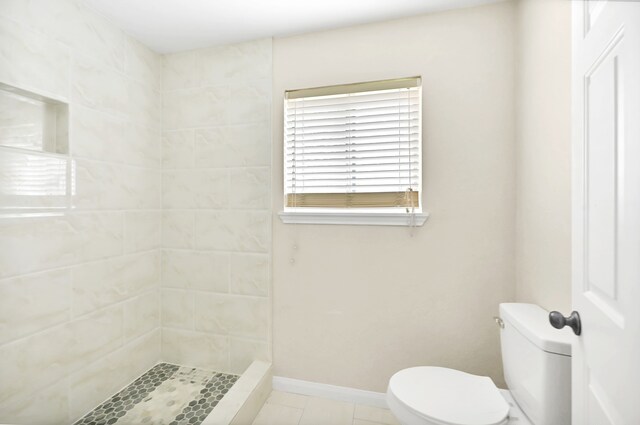 bathroom with tile flooring, a tile shower, and toilet