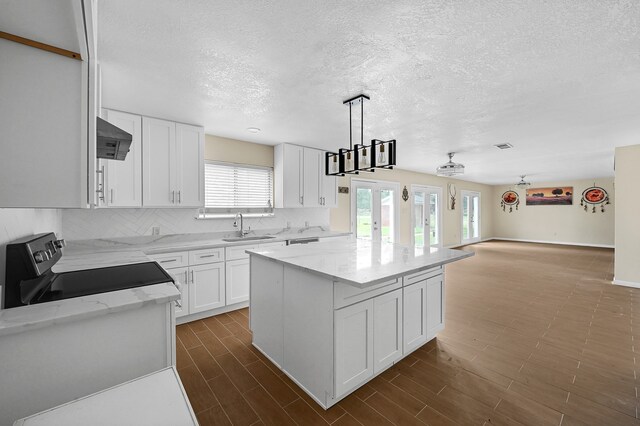 kitchen with a kitchen island, tasteful backsplash, white cabinetry, sink, and range with electric cooktop