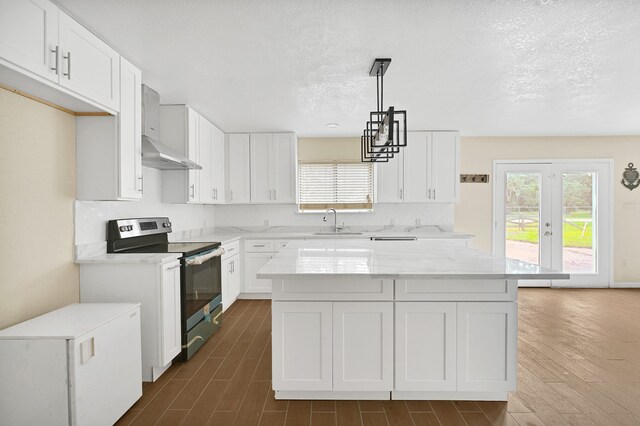 kitchen with a kitchen island, white cabinets, wall chimney range hood, and stainless steel electric stove