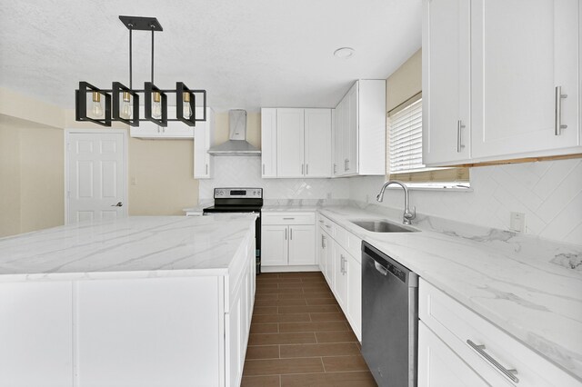 kitchen featuring decorative light fixtures, appliances with stainless steel finishes, wall chimney range hood, white cabinets, and sink