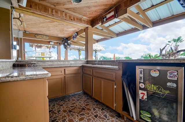 exterior space featuring dark tile floors, lofted ceiling with beams, light stone countertops, wooden ceiling, and sink