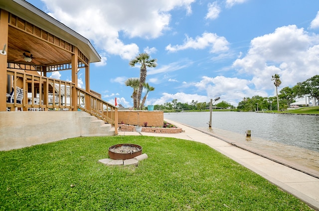 view of yard featuring a water view, ceiling fan, and an outdoor fire pit