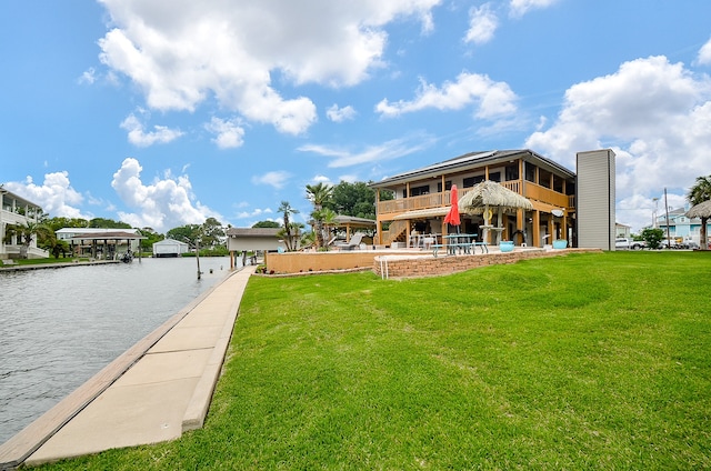 view of dock with a water view, a yard, and a balcony