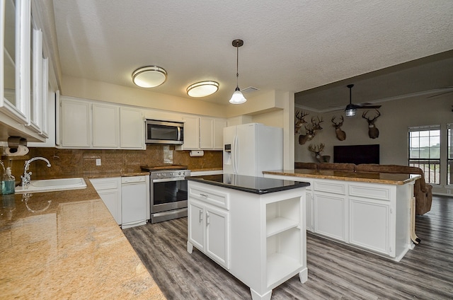 kitchen featuring appliances with stainless steel finishes, ceiling fan, a kitchen island, tasteful backsplash, and pendant lighting