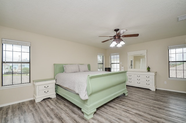 bedroom featuring multiple windows, ceiling fan, and hardwood / wood-style flooring