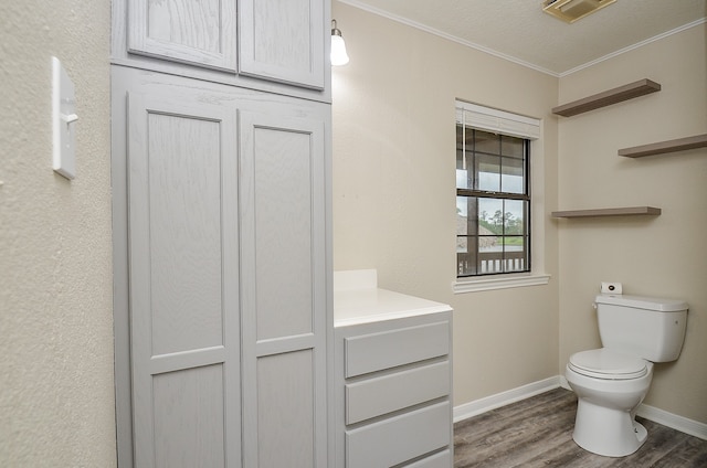 bathroom featuring a textured ceiling, crown molding, toilet, wood-type flooring, and vanity