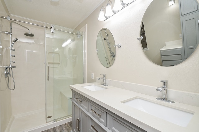 bathroom featuring hardwood / wood-style floors, double vanity, an enclosed shower, and a textured ceiling