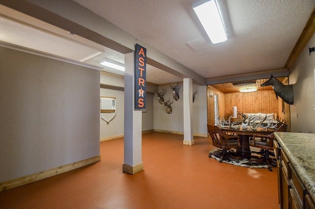 basement with wood walls, an AC wall unit, and a textured ceiling