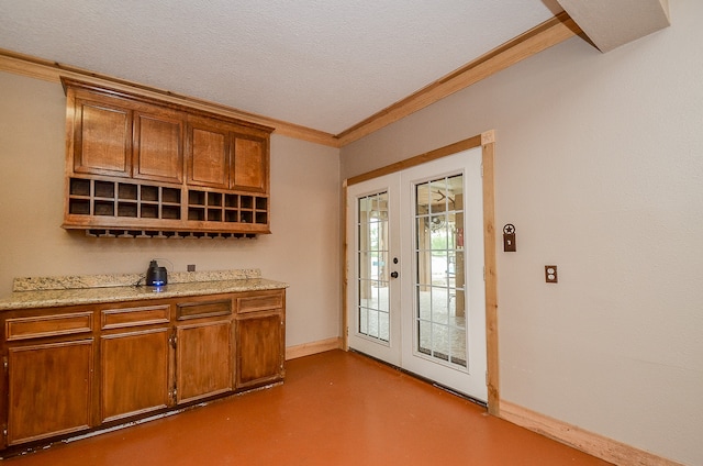 interior space featuring ornamental molding, french doors, a textured ceiling, and light stone counters