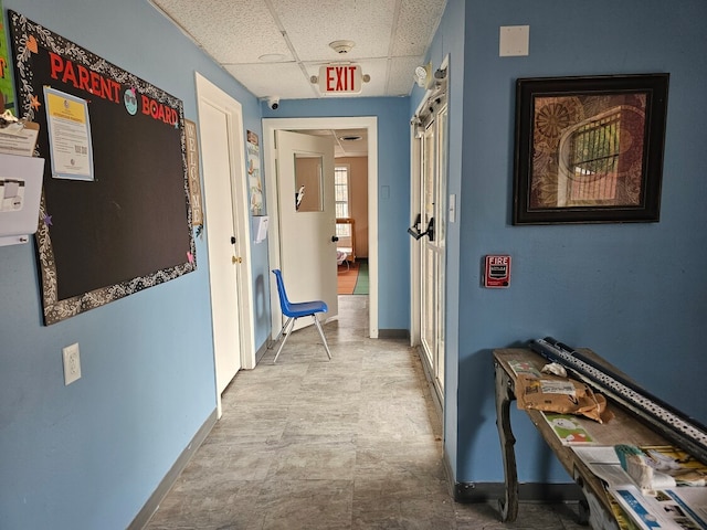 hallway with tile flooring and a drop ceiling