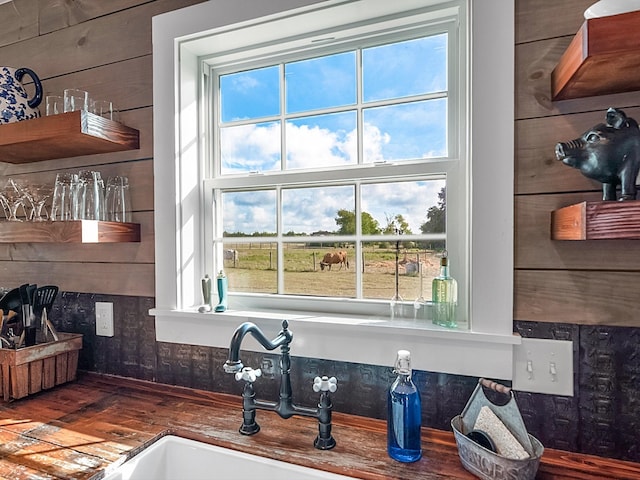 kitchen with hardwood / wood-style floors, sink, a wealth of natural light, and wooden walls