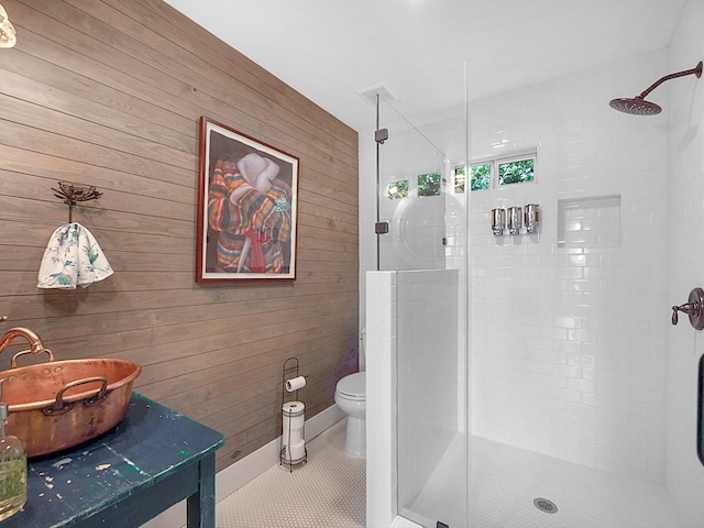 bathroom with wood walls, toilet, tile patterned floors, and a shower with shower door