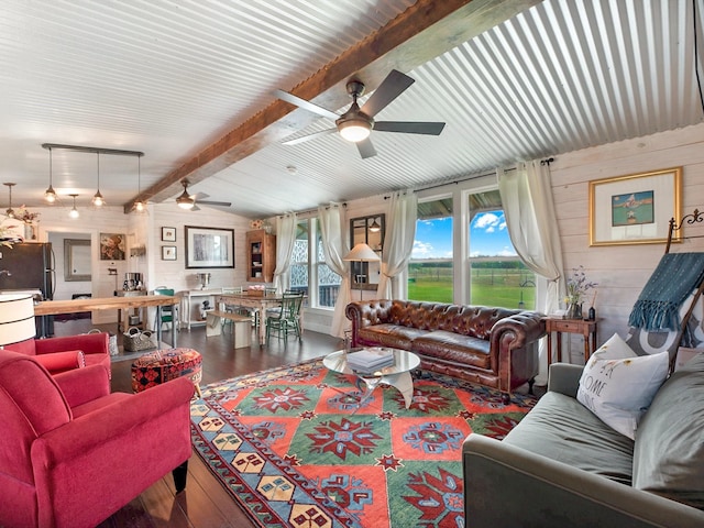 living room with ceiling fan, wood walls, hardwood / wood-style floors, and vaulted ceiling with beams