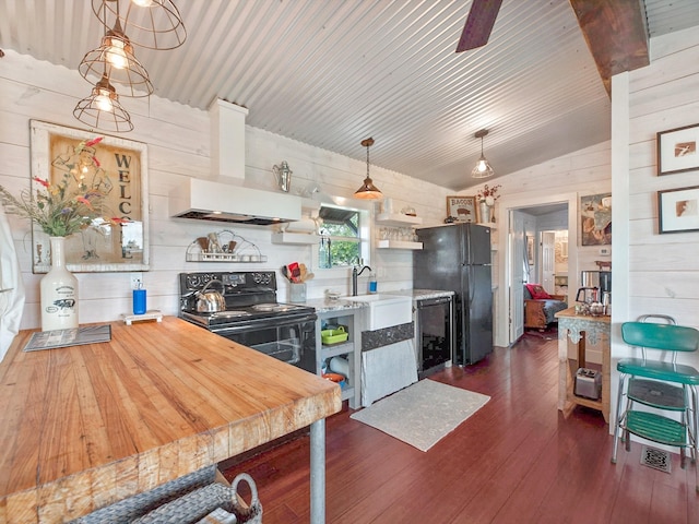 kitchen featuring pendant lighting, range hood, wood walls, dark hardwood / wood-style flooring, and black appliances