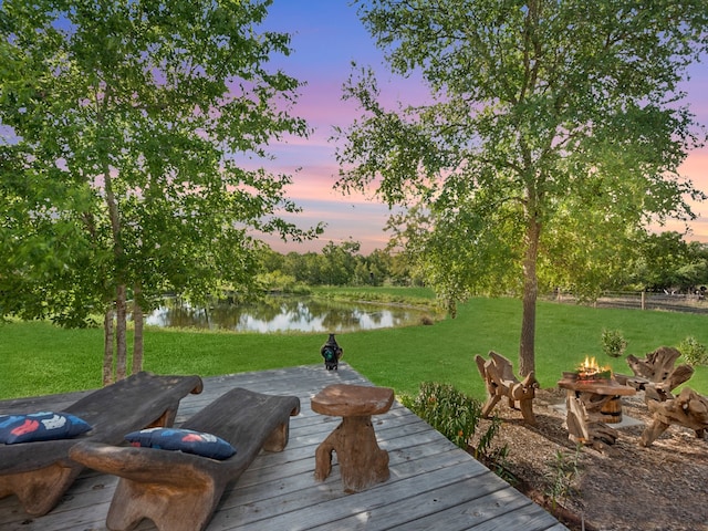 surrounding community featuring a water view, a lawn, and a fire pit