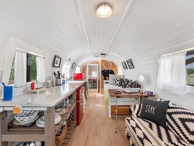 kitchen featuring vaulted ceiling, sink, light stone counters, wood ceiling, and light hardwood / wood-style flooring