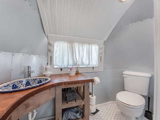 bathroom featuring tile patterned flooring, lofted ceiling, sink, and toilet