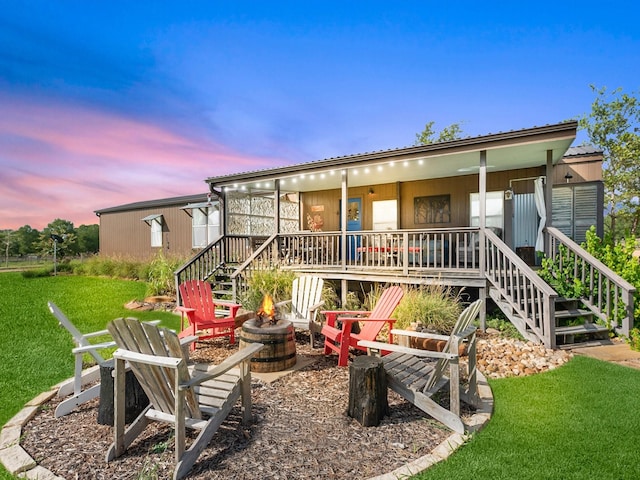 back house at dusk with a fire pit and a lawn