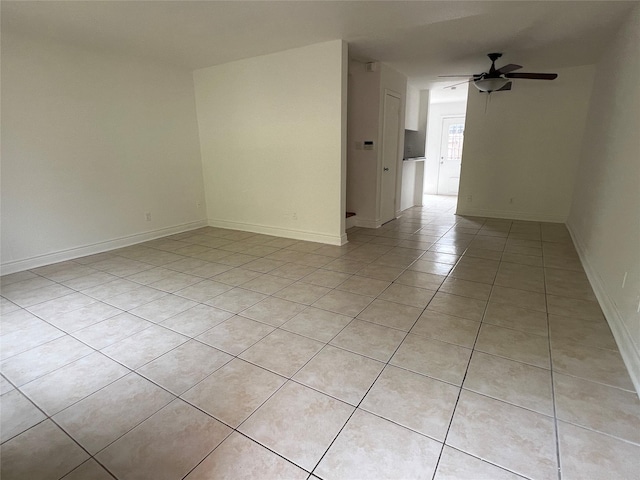 spare room with light tile patterned floors, baseboards, and a ceiling fan