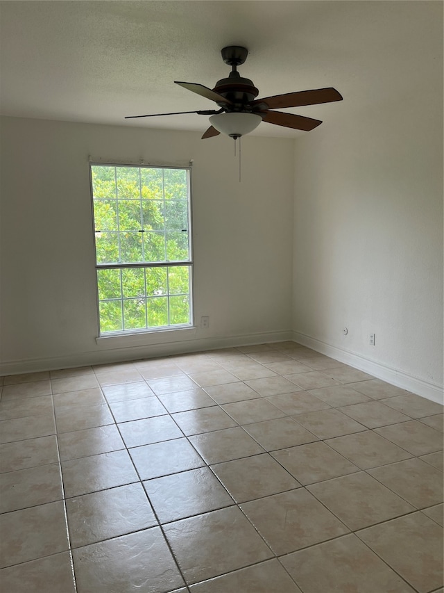 empty room with ceiling fan and light tile floors