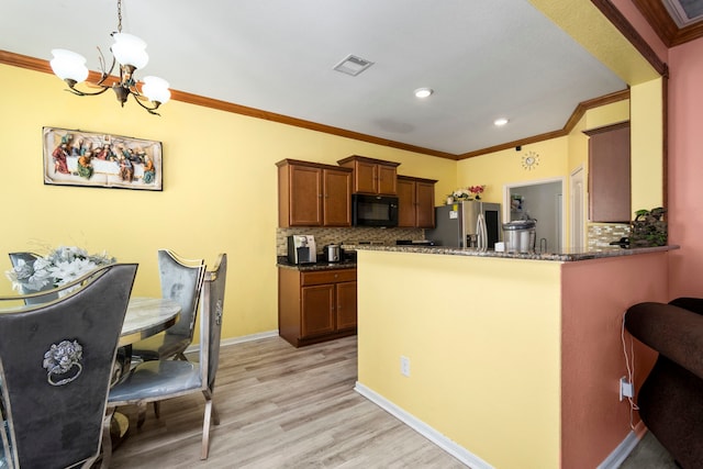 kitchen with decorative light fixtures, stainless steel fridge, tasteful backsplash, and light wood-type flooring