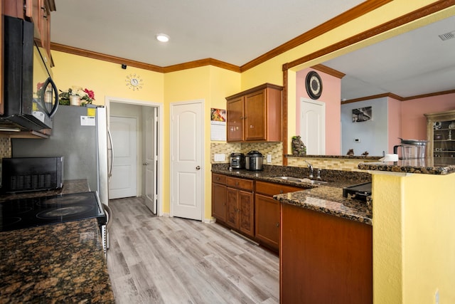 kitchen with backsplash, kitchen peninsula, sink, dark stone countertops, and light hardwood / wood-style floors