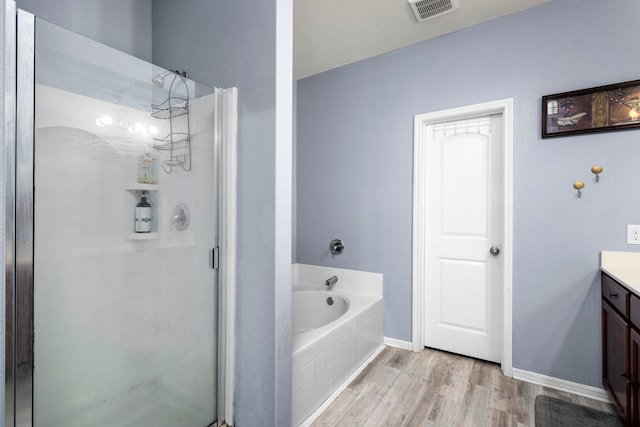 bathroom with wood-type flooring, independent shower and bath, and vanity