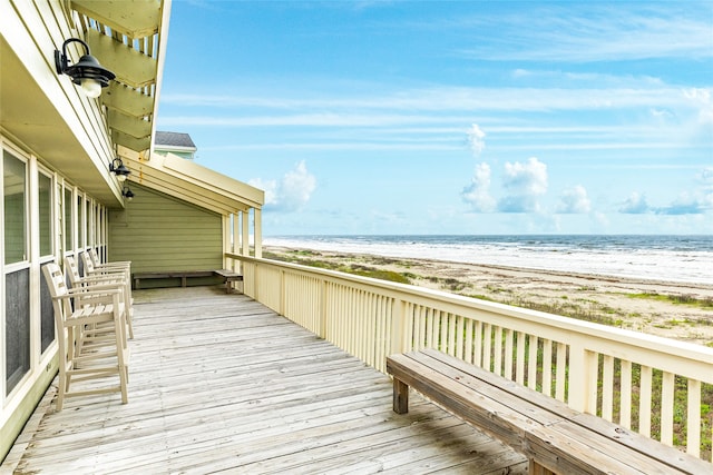 wooden terrace featuring a water view and a view of the beach