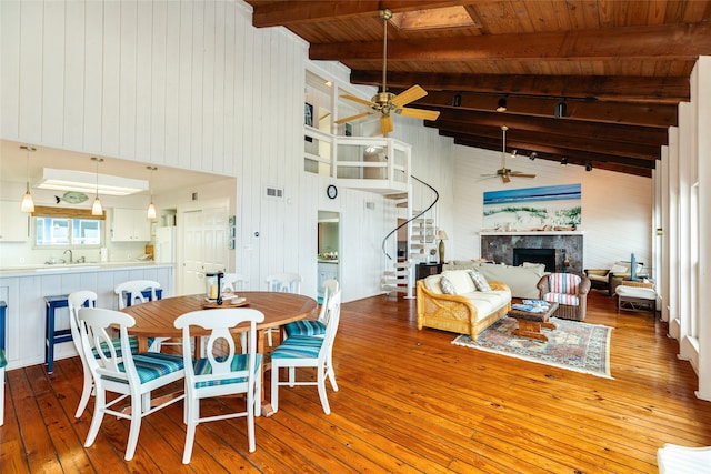 dining room featuring ceiling fan, sink, wood ceiling, a high end fireplace, and wood-type flooring