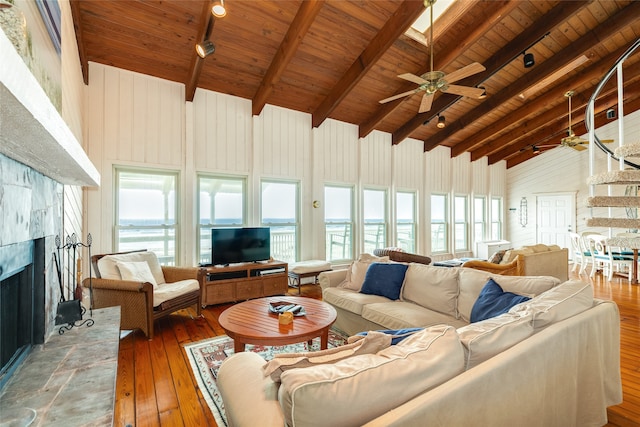 living room with wood ceiling, a stone fireplace, a healthy amount of sunlight, and hardwood / wood-style floors