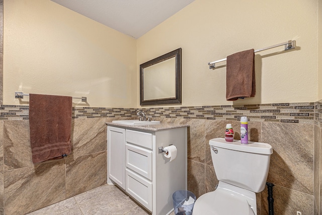 bathroom featuring tile patterned flooring, vanity, tile walls, and toilet